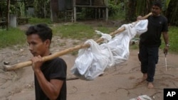 Thai rescuers carry a dead body to a hospital in Songkhla province, southern of Thailand Friday, May 1, 2015. Police in Thailand found dozens of shallow graves Friday and at least one corpse in an isolated mountain shelter that is believed to be a traffic