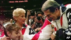 FILE - In this July 23, 1996, photo, Bela Karolyi, right, congratulates Dominique Moceanu, left, after the United States captured the gold medal in the women's team gymnastics competition at the Summer Olympic Games in Atlanta. U.S. team coach Martha Karolyi looks on. 
