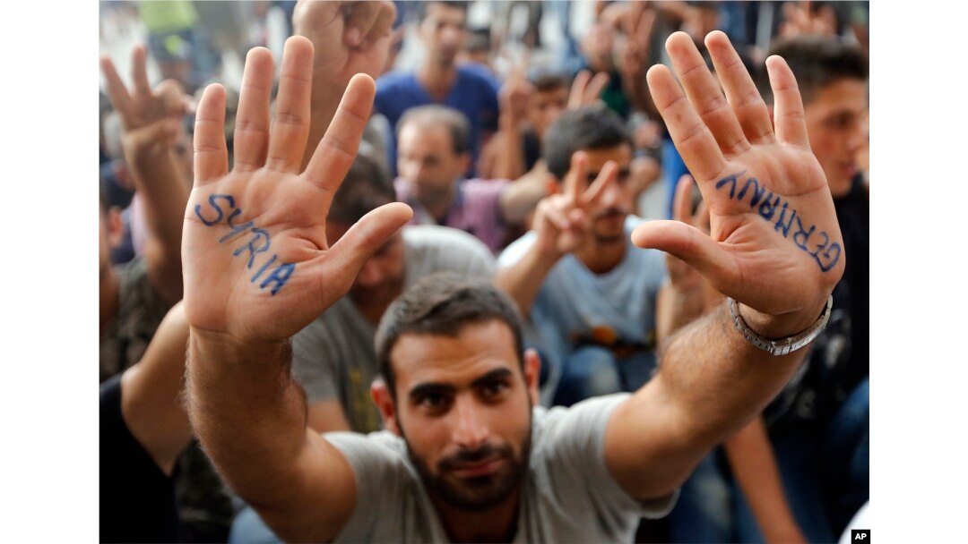 A migrant shows his painted hands in front of the railway station in Budapest, Hungary, Sept. 3, 2015.