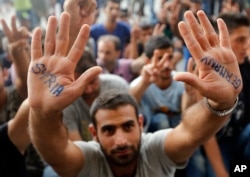 A migrant shows his painted hands in front of the railway station in Budapest, Hungary, Sept. 3, 2015.