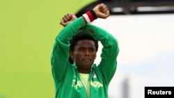 Silver medalist Feyisa Lilesa, of Ethiopia, acknowledges applause during an award ceremony as he crosses his wrists in an attempt to draw global attention to recent deadly protests in his home region, Oromia, after the men's marathon at the 2016 Summer Olympics