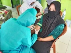 Petugas medis mengenakan APD mengambil sampel darah untuk pemeriksaan tes cepat salah satu anggota Panitia Pemungutan Suara di Puskesmas Kecamatan Lage, Kabupaten Poso, Sulawesi Tengah, 25 Juni 2020. (Foto: KPU Kabupaten Poso)