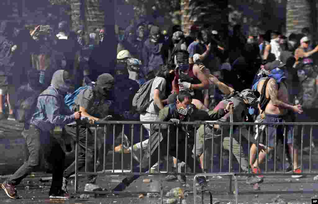 Manifestantes enmascarados chocan con la policía en Santiago, Chile, el lunes 21 de octubre de 2019. (Foto AP / Luis Hidalgo).