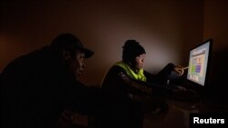 Homeless high school student Frank Hardy looks over homework with his mother at the PATH shelter where they live in Los Angeles, Dec. 9, 2021. 