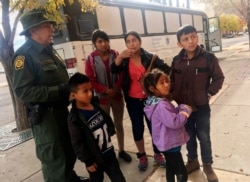 A migrant family from Central America waits outside the Annunciation House shelter in El Paso, Texas, Nov. 29, 2018, after a U.S. Immigration and Customs Enforcement officer drops them off.
