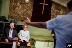 FILE —Former President Jimmy Carter, left, sits with his wife, Rosalynn, as they wait to pose for photos after Carter taught Sunday School class at Maranatha Baptist Church in his hometown of Plains, Ga., Sunday, Aug. 23, 2015.