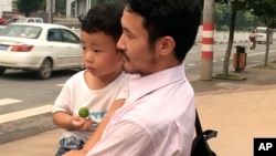 Chinese labor activist Hua Haifeng, center, carries his son Bobo chats with his sister Hua Xiaoqin, left, as they leave a police station after being released in Ganzhou in southern China's Jiangxi Province, June 28, 2017. 