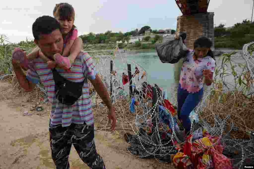 Migrants from Venezuela make their way through the razor wire after crossing the Rio Grande into the United States in Eagle Pass, Texas, Sept. 26, 2023.