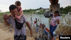 Sejumlah migran dari Venezuela berjalan melewati kawat berduri setelah menyeberangi sungai Rio Grande di Eagle Pass, Texas, pada 26 September 2023. (Foto: Reuters/Brian Snyder)