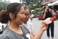 This photo taken on July 12, 2018 shows a woman looking at polluted water in a mineral water bottle at a roving exhibition created by Chinese performance artist Brother Nut.