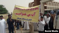 In this photo shared on social media, Iranian farmers gather outside the Khuzestan provincial government complex in the southern city of Ahvaz, May 16, 2018, to protest a provincial ban on rice-planting due to water shortages. The protesters hold a sign saying, “We need water to make a living – Rice farmers of Khuzestan.”