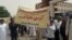 In this photo shared on social media, Iranian farmers gather outside the Khuzestan provincial government complex in the southern city of Ahvaz, May 16, 2018, to protest a provincial ban on rice-planting due to water shortages. The protesters hold a sign saying, “We need water to make a living – Rice farmers of Khuzestan.”
