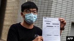 Pro-democracy activist Joshua Wong speaks to media while holding up a bail document after leaving police station in Hong Kong, September 24, 2020, after being arrested for unlawful assembly related to a 2019 protest against a government ban on face masks.