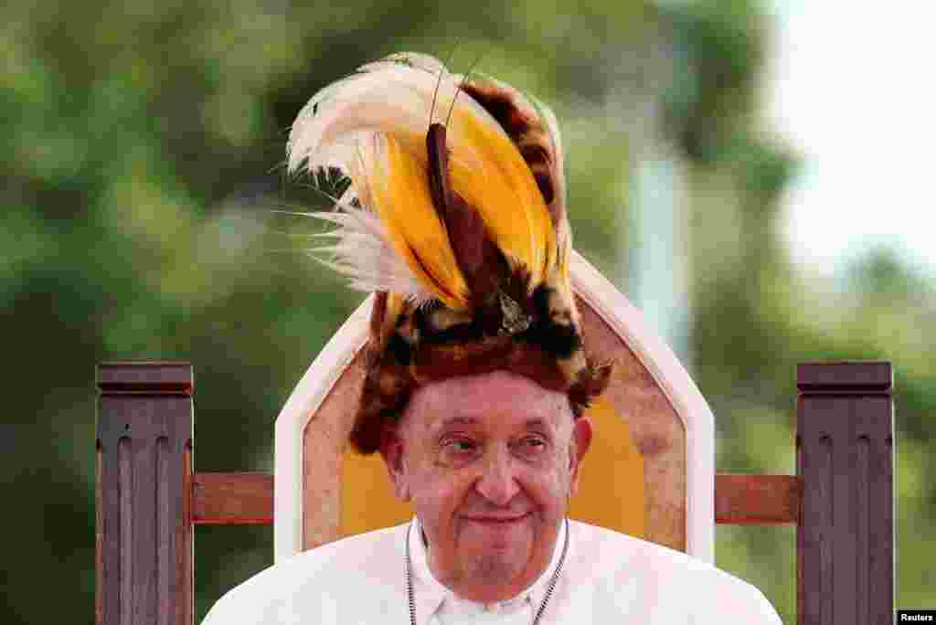 Pope Francis sits with headgear as he visits Vanimo, Papua New Guinea.