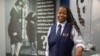 Keturah Johnson, international vice president for flight attendant union AFA-CWA, poses by a decades-old, outdated poster about rules and uniforms for flight attendants, at her headquarters office in Washington, Sept. 18, 2024. 