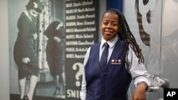 Keturah Johnson, international vice president for flight attendant union AFA-CWA, poses by a decades-old, outdated poster about rules and uniforms for flight attendants, at her headquarters office in Washington, Sept. 18, 2024. 