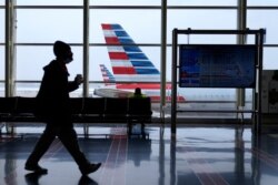 Sebuah jet American Airlines duduk diparkir di gerbang saat salju tipis turun di Bandara Nasional Ronald Reagan Washington, Selasa, 2 Februari 2021, di Arlington. (Foto: AP)
