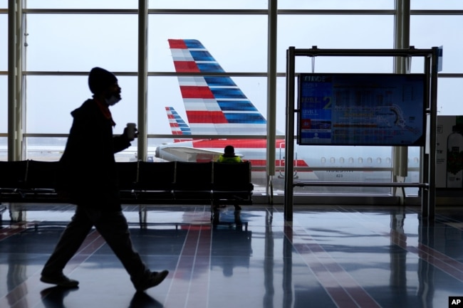Sebuah jet American Airlines duduk diparkir di gerbang saat salju tipis turun di Bandara Nasional Ronald Reagan Washington, Selasa, 2 Februari 2021, di Arlington. (Foto: AP)