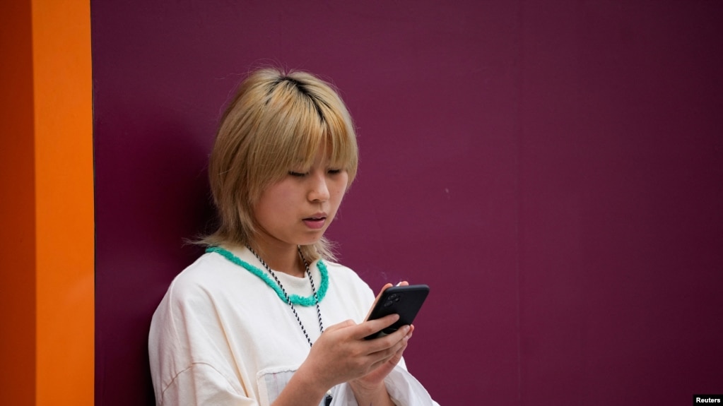 一名中国女子在街上使用苹果手机。（路透社2023年9月27日）(photo:VOA)