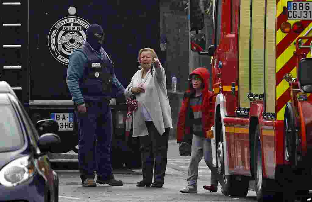 A woman speaks with a police officer near a building where the chief suspect in Toulouse, March 22, 2012. (AP)