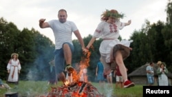 People jump over a campfire as they take part in the Ivan Kupala festival in Belarusian state museum of folk architecture and rural lifestyle near the village Aziarco, July 4, 2020.