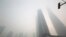 FILE - An electronic screen and buildings are seen amid heavy smog at the financial district of Pudong in Shanghai, Dec. 6, 2013.