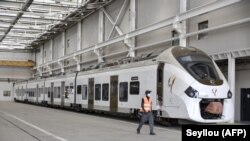 Un agent du train express régional (TER) passe devant un train stationné au service de maintenance et de stockage de Colobane, à Dakar, au Sénégal, le 22 décembre 2021.