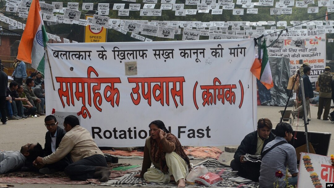 Para demonstran duduk di depan spanduk memprotes pemerkosaan dan pembunuhan Desember lalu terhadap seorang perempuan di New Delhi (2/1) 