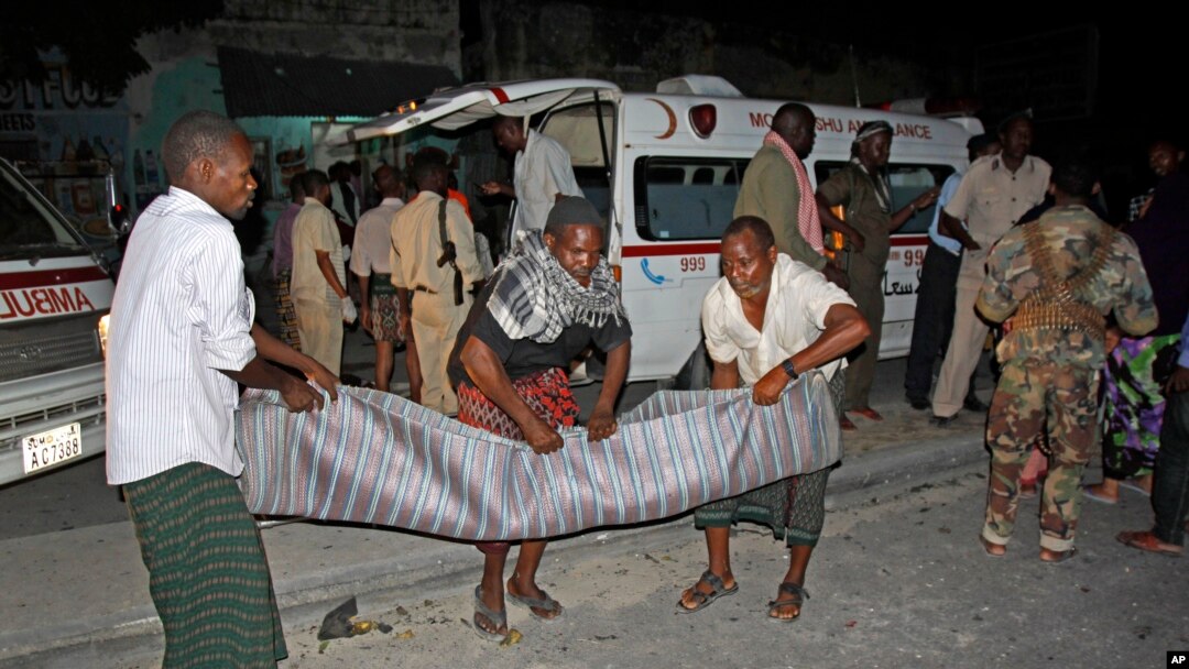 Warga di Mogadishu mengangkut korban tewas dalam ledakan di dekat cafe di Mogadishu (12/10).
