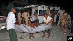 Warga di Mogadishu mengangkut korban tewas dalam ledakan di dekat cafe di Mogadishu (12/10).