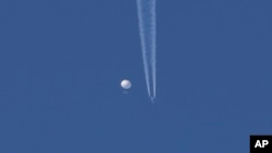 一个大气球漂浮在北卡罗来纳州金斯顿上空，它下面可以看到一架飞机和它留下的轨迹。