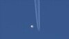 Sebuah balon besar melayang di atas area Kingston, dengan sebuah pesawat terbang terlihat di bawahnya. (Foto: via AP)