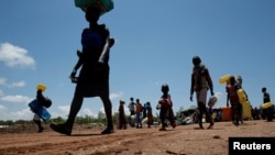 FILE - A South Sudanese refugee woman carries her belongings in a refugee settlement camp in northern Uganda, Aug. 23, 2017. 