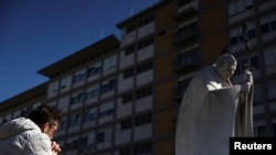 Un hombre reza junto a la estatua del difunto Papa Juan Pablo II en el exterior del Hospital Gemelli, donde el Papa Francisco está ingresado para recibir tratamiento, en Roma, Italia, el 4 de marzo de 2025.