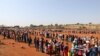 People stand in a queue to receive food aid amid the spread of the coronavirus disease (COVID-19), at the Itireleng informal settlement, near Laudium suburb in Pretoria, South Africa.