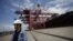 An employee stands next to a container ship at Ningbo port in Ningbo, Zhejiang province, June 21, 2012. 