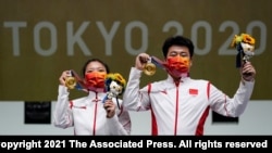 Gold medalists Jiang Ranxin, and Pang Wei, of China, celebrate after the mixed team 10-meter air pistol at the Asaka Shooting Range in the 2020 Summer Olympics, July 27, 2021, in Tokyo, Japan.