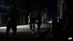 A man walks along a street with the aid of crutches during a massive blackout after a major power plant failed in Havana, Oct. 18, 2024.