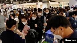 People wearing masks to prevent contracting the coronavirus wait in line to buy masks at a department store in Seoul, South Korea, Feb. 27, 2020.