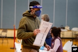 Julian St. Laurent wear a face shield and two face masks to help prevent the spread of the coronavirus as he walks to a voting both to cast his ballot to vote on Election Day, Nov. 3, 2020, in Portland, Maine.