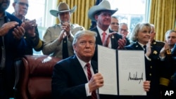 President Donald Trump signs the first veto of his presidency in the Oval Office of the White House, March 15, 2019, in Washington. Trump issued the first veto, overruling Congress to protect his emergency declaration for border wall funding.