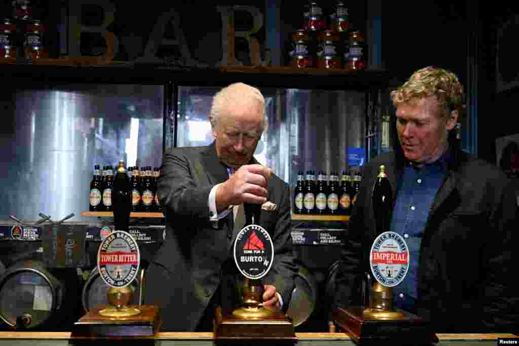 Britain&#39;s King Charles pulls a pint alongside Tower Brewery owner John Mills, during a visit to the Tower Brewery in Burton-Upon-Trent.