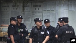 Chinese policemen huddle near the Chengdu Intermediate People's Court in Chengdu in southwest China's Sichuan province, Sept. 17, 2012.