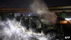 Asap mengepul dari sisa kendaraan milik pasukan perdamaian PBB di Lebanon (UNIFIL) yang dibakar para pedemo di jalan menuju Bandara Internasional Beirut, Jumat, 14 Februari 2025. (Foto: Ibrahim Amro/AFP)