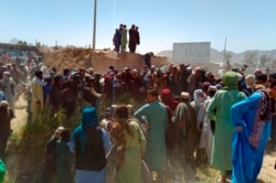 Taliban fighters and Afghans gather around the body of a member of the security forces who was killed, inside the city of Farah, capital of Farah province, southwest Afghanistan, Aug. 11, 2021.