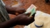 Un commerçant malawite compte son argent alors qu'il vend du maïs près de la capitale Lilongwe, au Malawi, le 1er février 2016. 