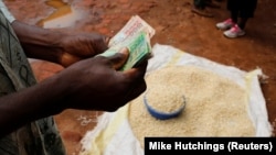 FILE - Malawi maize seller counts his cash near the capital, Lilongwe, on February 1, 2016. Malawi's foreign exchange reserves in the first quarter of 2022 sharply dropped compared to the fourth quarter of 2021 according to a new report.