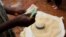 FILE - Malawi maize seller counts his cash near the capital, Lilongwe, on February 1, 2016. Malawi's foreign exchange reserves in the first quarter of 2022 sharply dropped compared to the fourth quarter of 2021 according to a new report.