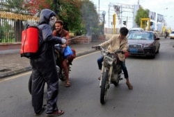 Yemeni security personnel of the Central Security Forces, wearing full PPE, disinfect a man on a motorcycle in the Huthi-rebel-held capital Sanaa on May 23, 2020.