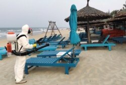 A health worker sprays disinfectants to protect against the coronavirus on a beach in Hoi An, Vietnam, March 10, 2020.